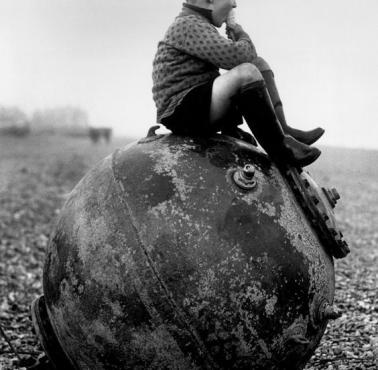 Chłopiec siedzi na rozbrojonej niemieckiej minie, plaża w Kent, Anglia, 1945